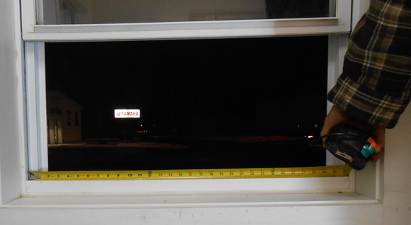 Person using a tape measure to measure a window opening before ordering a window dryer vent by vent works